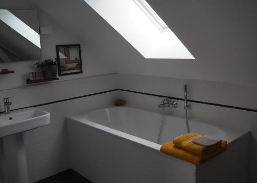 a bathroom with a tub and a sink and a skylight at Entre en Baie ! in Pontaubault