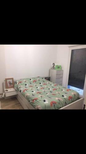 - une chambre avec un lit doté d'une couette verte et d'une fenêtre dans l'établissement T2 jardin à deux pas de la mer, à Saint-Cyr-sur-Mer