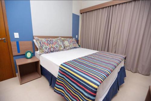 a bedroom with a bed with a colorful striped blanket at Apartamento 2 quartos Lazer Completo in Caldas Novas