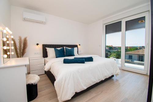 um quarto branco com uma cama grande e almofadas azuis em Villa Mina with a private pool in Pula em Pula
