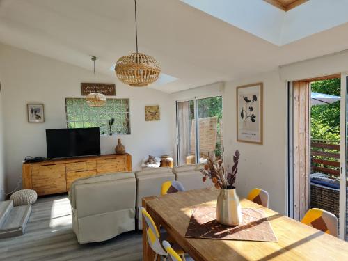 sala de estar con mesa de comedor y TV en La Maison des 4 moineaux, en Lons-le-Saunier