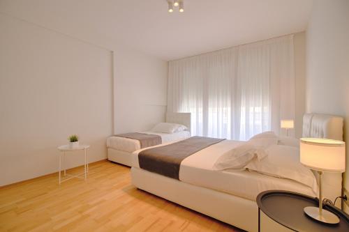 a bedroom with two beds and a table and a window at The Rooms Serviced Apartments Tirana in Tirana