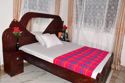 a bedroom with a wooden bed with a red and blue blanket at Donita's Seaview Apartments in Mombasa