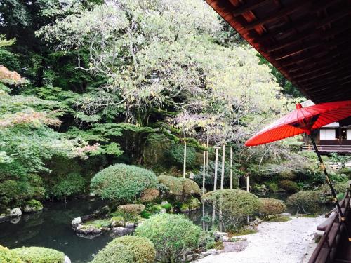 a red umbrella in front of a garden with a stream at Enmanin Sanmitsuden - Vacation STAY 39449v in Otsu