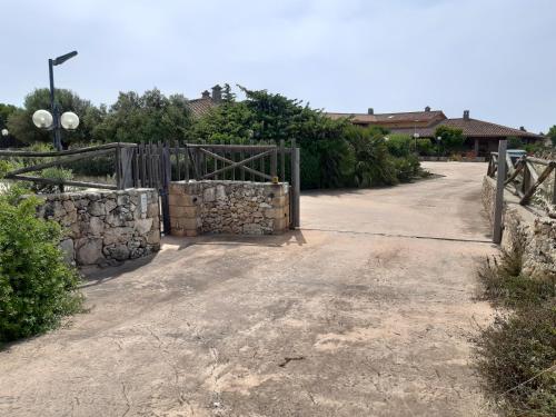 a gate in a driveway with a stone wall at Casa S'arena in Putzu Idu