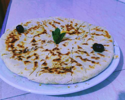 a pizza with a green leaf on a white plate at Auberge La Fibule Du Dades in Aït Idaïr