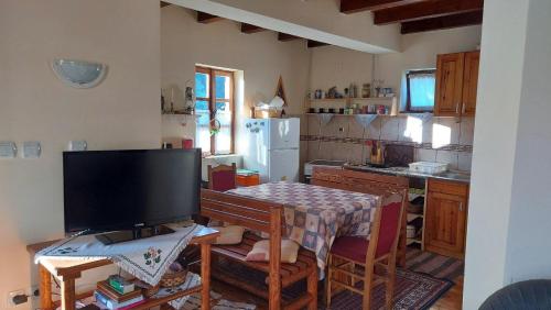 eine Küche mit einem TV und einem Tisch mit einem Tisch in der Unterkunft Apartment ''Planinsko selo'' in Zaovine