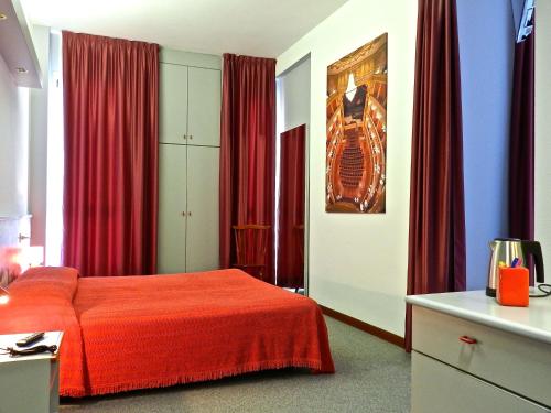 a bedroom with a red bed and red curtains at Hotel Italia in Stradella
