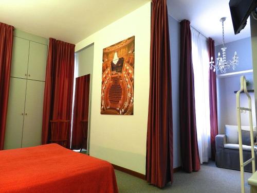 a bedroom with red curtains and a bed with a picture on the wall at Hotel Italia in Stradella