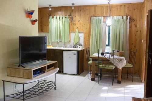 sala de estar con TV y mesa con cocina en צימר בלוטים באמנון, en Amnon