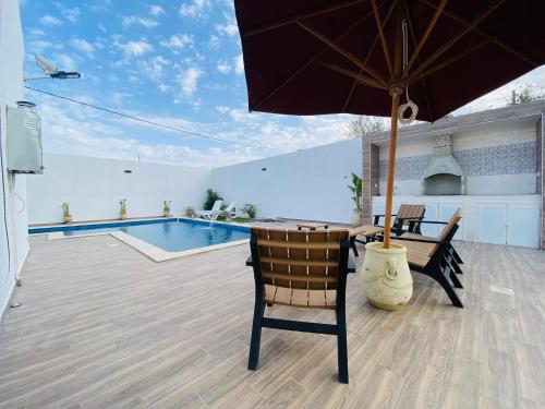 a patio with a table and an umbrella and a pool at Super villa midoun in Djerba