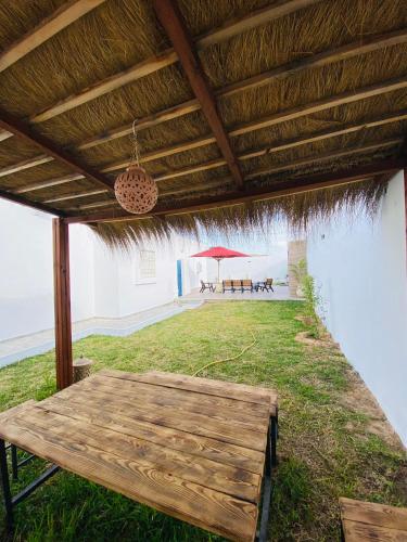 a wooden picnic table under a roof with a view of the beach at Super villa midoun in Djerba