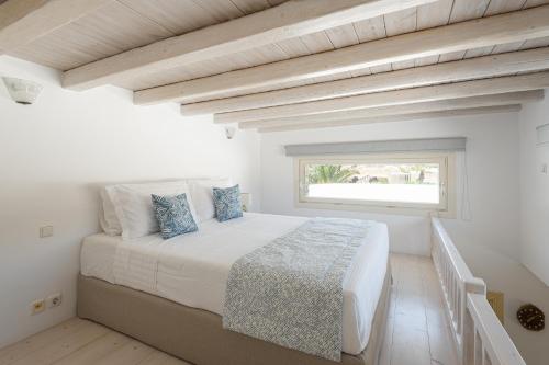 a white bedroom with a large bed with a window at Etesians Suites & Villas in Super Paradise Beach