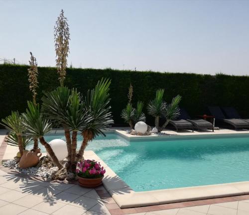 a swimming pool with palm trees and plants at Casa di Campagna B&B La Corte Ferrara in Ferrara