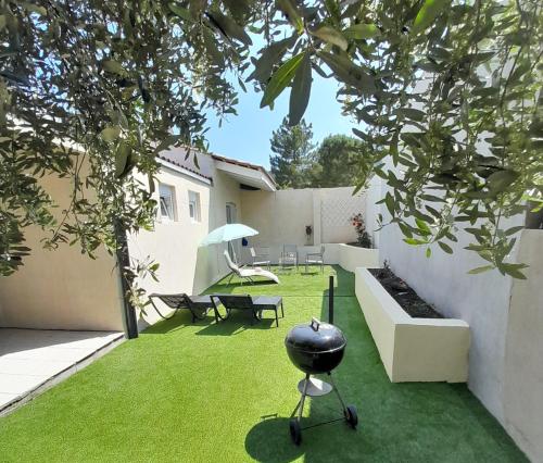 - un jardin avec une chaise, une table et un parasol dans l'établissement L'olivier TESSA Hôtesse suite 30m2 terrasse 20m2, à La Celle