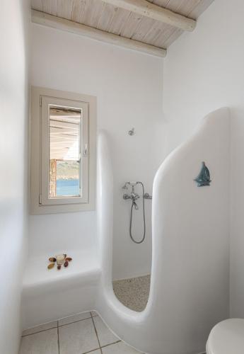 a white bathroom with a tub and a window at Etesians Suites & Villas in Super Paradise Beach