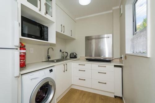 a kitchen with a washer and a sink and a microwave at Harbour View Guesthouse in Auckland