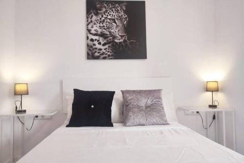 Un dormitorio con una cama blanca con una foto de un leopardo en Des Artistes Lloret de Mar en Lloret de Mar