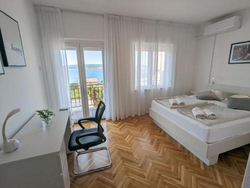 a white bedroom with a bed and a chair at Apartment Arya in Crikvenica