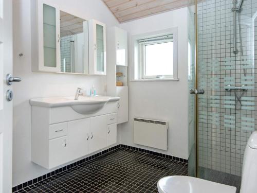 ein weißes Bad mit einem Waschbecken und einer Dusche in der Unterkunft Holiday Home As Hedegård II in Sønderby