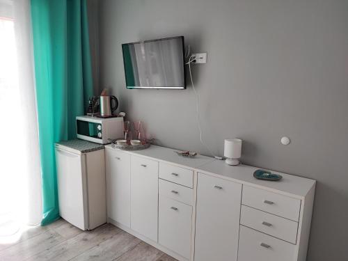 a kitchen with white cabinets and a tv on the wall at 4 Foxes in Ustka