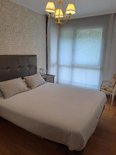 a large white bed in a bedroom with a chandelier at Apartamento en el centro con garaje directo. in Bilbao