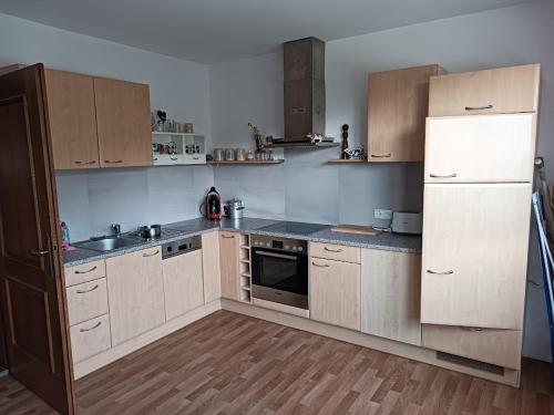 una cocina con electrodomésticos blancos y armarios de madera en Kuhstall Appartement, en Weiler
