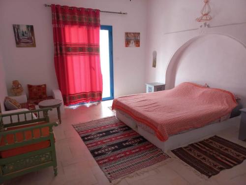 a bedroom with a bed and red curtains and a rug at villa la rose des sables in Midoun