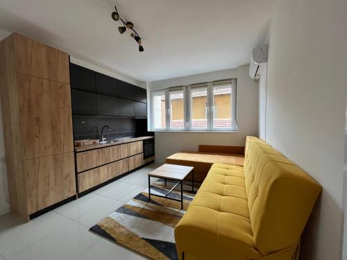 a living room with a yellow couch and a kitchen at Apartment Monaliza in Pirot