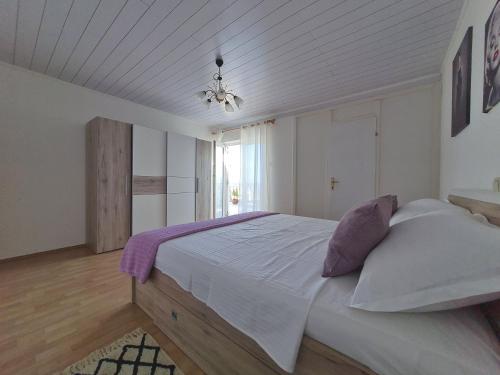 1 dormitorio con 1 cama grande con sábanas blancas y almohadas moradas en Apartman Tea, en Novi Vinodolski