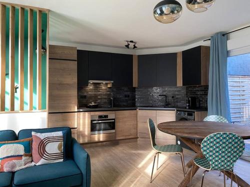 une cuisine avec un canapé bleu, une table et des chaises dans l'établissement Luminieuse maison de pêcheur avec terrasse, à Saint-Valery-sur-Somme