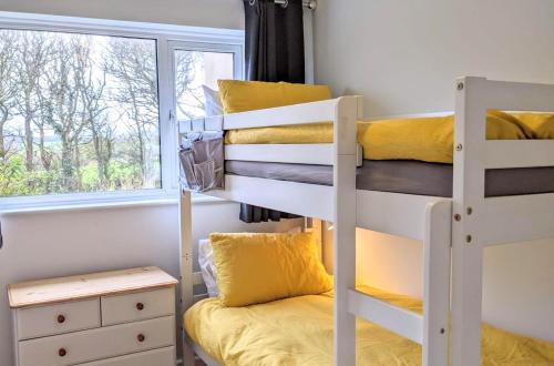 1 dormitorio con 2 literas y ventana en Comfortable bungalow near Widemouth Bay beach, en Poundstock