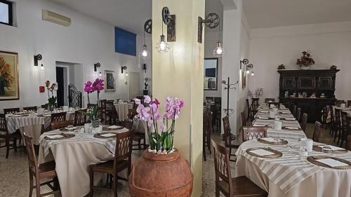 una sala da pranzo con tavoli e sedie con fiori viola di Hotel Il Gioiello a Sabaudia