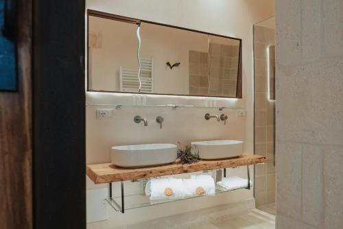 La salle de bains est pourvue de 2 lavabos et d'un miroir. dans l'établissement Masseria Le Lamie, à Villa Castelli