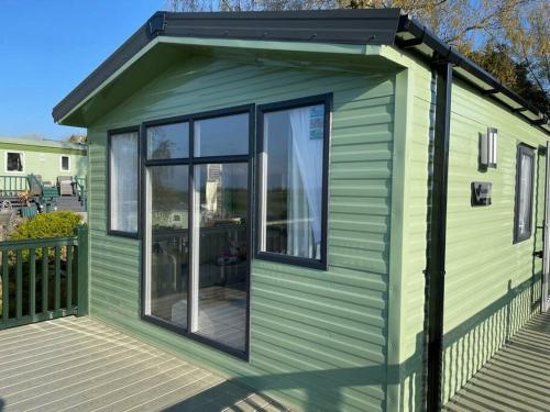 a green tiny house with large windows on a deck at The Lookout-Ribble Valley. Amazing home Gisburn in Gisburn