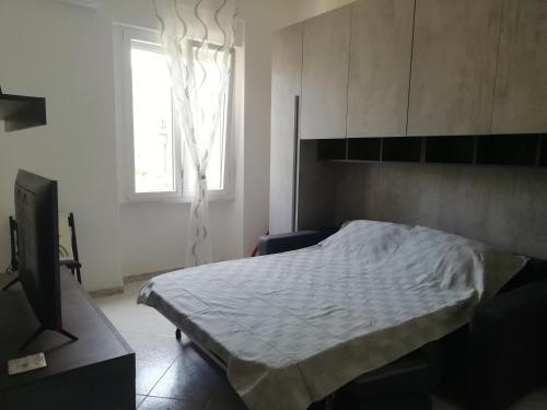 Schlafzimmer mit einem Bett, einem TV und einem Fenster in der Unterkunft Casa Clara Oristano centro con giardino in Oristano