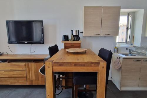 Il comprend une cuisine avec une table en bois, des chaises et une télévision. dans l'établissement Appartement T2 en bord de mer, à Marseille