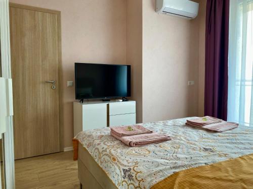 a room with a bed with a television and towels at AVRORA in Varna City
