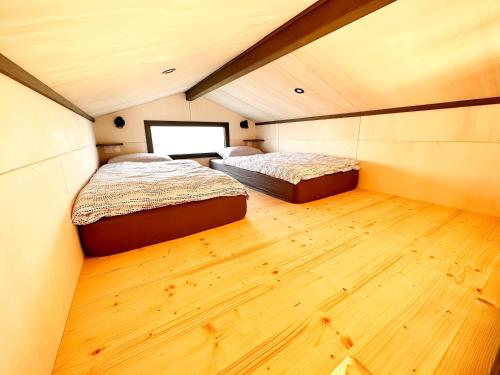 two beds in a small room with wood floors at tiny house in Cholet