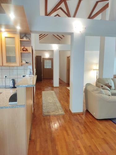 a living room with a white couch and a kitchen at Vila Gardenia in Sarajevo