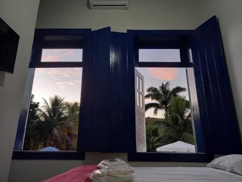 a bedroom with a window with a view of a palm tree at Pousada Usina Paraíso in Astolfo Dutra