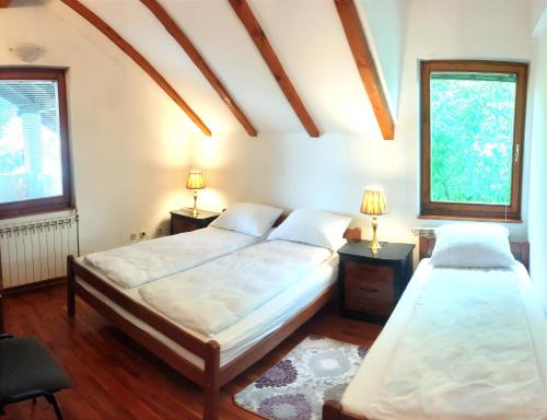 two beds in a room with two windows at Vila Gardenia in Sarajevo