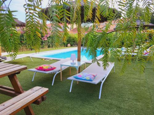 - une table et deux chaises à côté de la piscine dans l'établissement Villa les Flamants roses, à Torreilles