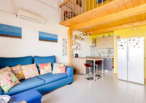 a living room with a blue couch and a kitchen at Villa Bellavista IS MOLAS PULA, CAGLIARI in Santa Margherita di Pula