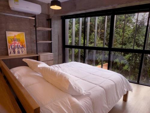 um quarto com uma cama branca e uma grande janela em Insula Living Juanambu em Cali