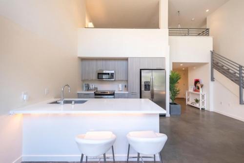 une cuisine avec un comptoir et deux tabourets blancs dans l'établissement 1500 Sq foot, 3 bed room loft in DTLA (Pool & Hot tub!), à Los Angeles