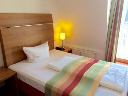 ein Schlafzimmer mit einem Bett mit gestreifter Decke in der Unterkunft Hotel Ambert in Berlin
