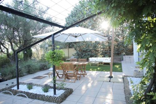 un patio avec une table et un parasol dans l'établissement Le Jardin d'Eden, à Tavernes