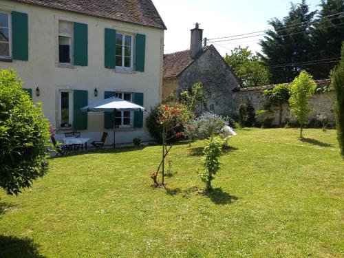 a garden in front of a house with an umbrella at L'ancien prieuré in Lorrez-le-Bocage