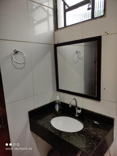 ein Bad mit einem Waschbecken und einem Spiegel in der Unterkunft Sítio Vista da Serra in Lavrinhas